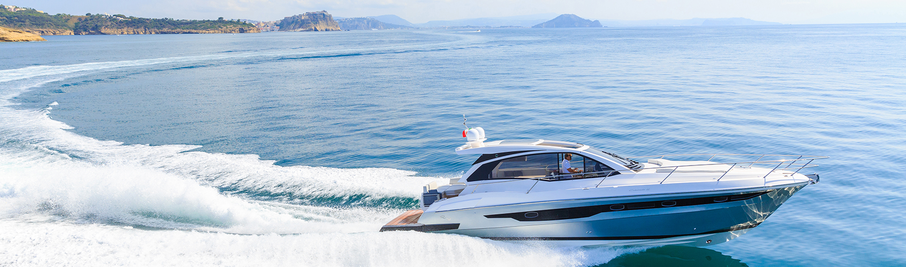 High Net Worth Insurance: A man driving a luxury speed boat across the sea
